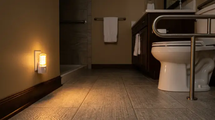 Motion-sensor amber night light at floor level in a senior bathroom