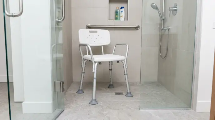 Diagram showing uneven shower chair leg height adjustment to compensate for a sloped shower pan