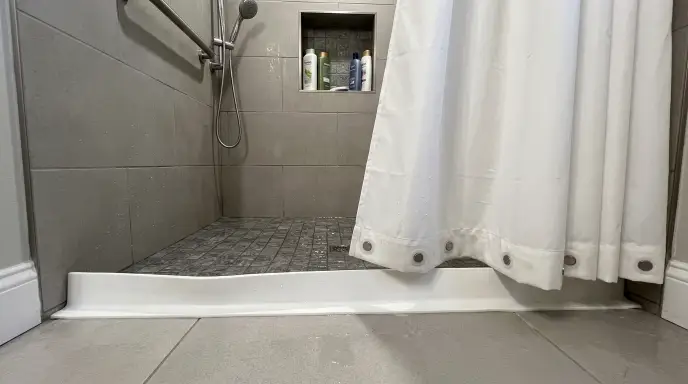 weighted shower curtain with a flexible collapsible rubber water dam to prevent bathroom slips